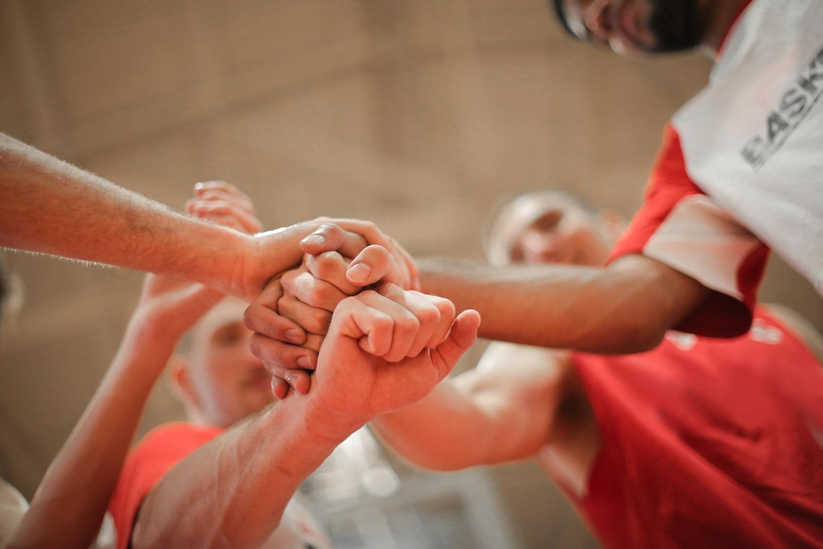 A multiethnic team of professional basketball players gathering and putting hands together